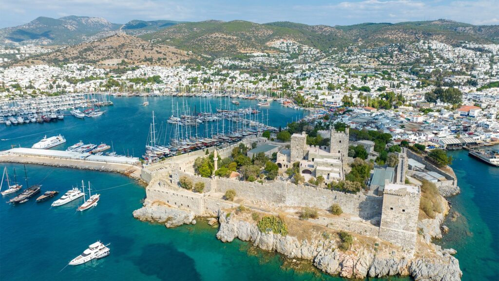 Bodrum Castle and marina aerial view showing luxury yachts, sailing boats and the historic Castle of St. Peter surrounded by turquoise waters - premier yacht charter destination in Turkey